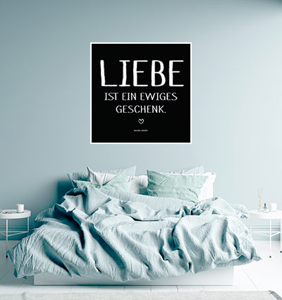 schwarzweisses Schriftbild mit Spruch Liebe ist hängend an Wand über Bett